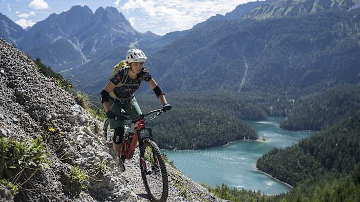 Eine Frau fährt mit ihrem Fahrrad entlang einer Radstrecke entlang und wird dabei von einem spektakulären Panorama begleitet.