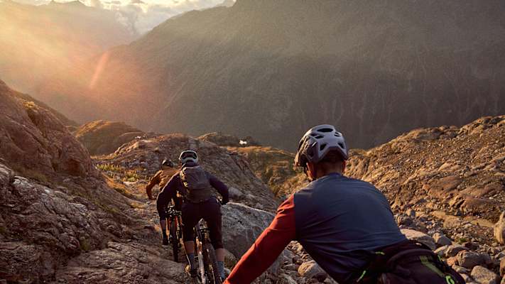 Drei Radfahrer fahren der Sonnen beim Sonnenuntergang entgegen.