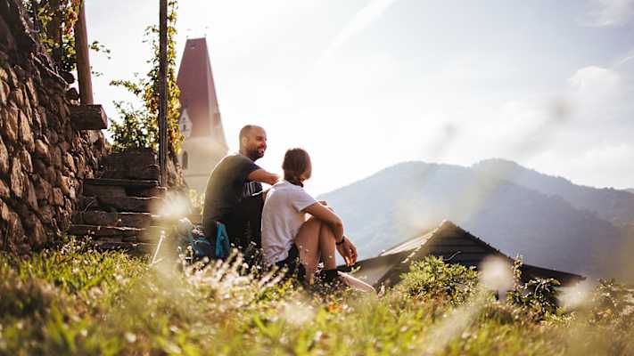 Zwei Personen sitzen auf einer Almwiese und genießen den Ausblick in Niederösterreich