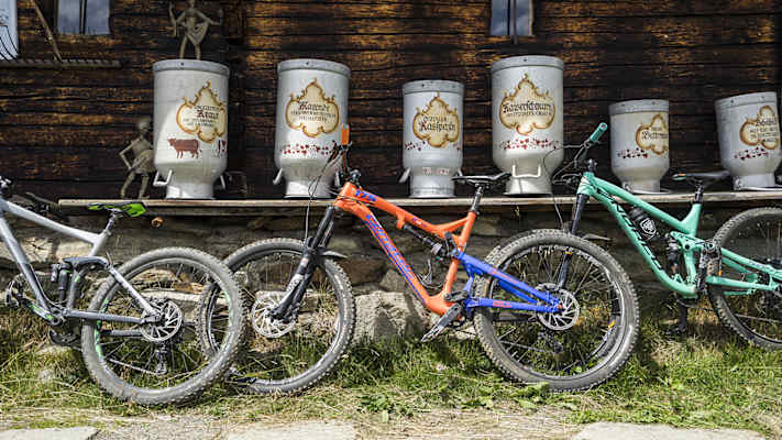 Drei Fahrräder sind an ein Holzhaus angelehnt.