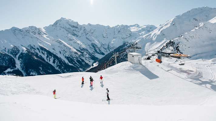 Skifahrer stehen vor einer Liftanlage.