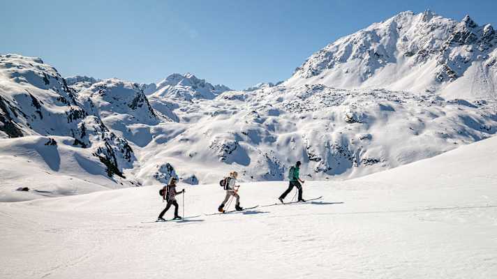 Drei Skitourengeher begeben sich auf eine Tour auf unberührten Pfaden.