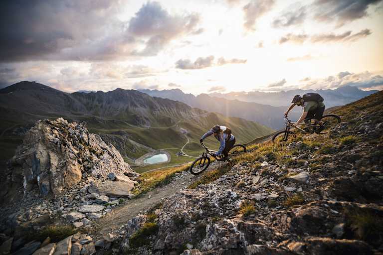 Mountainbiker fahren in eindrucksvoller Gebirgslandschaft bergab