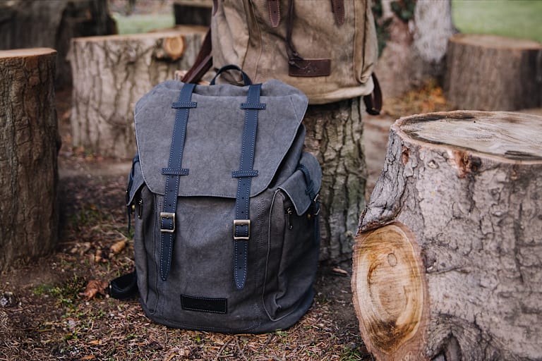 Der große Wanderrucksack von Servus in Grau in der Natur zwischen Baumstämme.