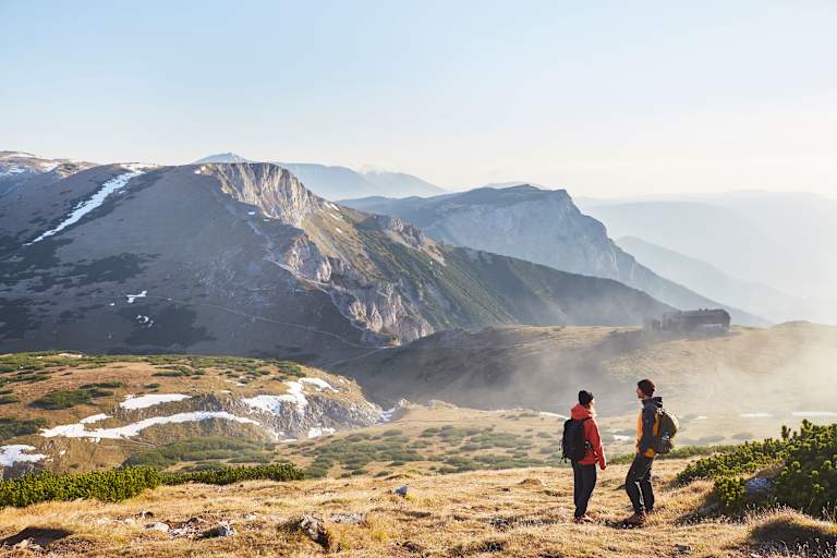 Morgennebel umspielt das Raxplateau beim Anstieg zur Heukuppe (2.007 m). Der Blick zurück wendet sich dem Karl Ludwig Haus und dem Predigtstuhl (li.) zu.