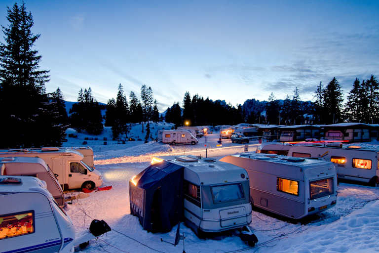 Der Wintercampingplatz Jaunpass bei Nacht. Es liegt Schnee und die Wohnwagen sind hell erleuchtet.
