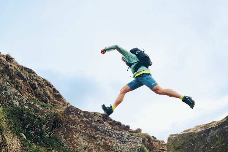 Ein Mann trägt den neuen Remote Hike 23L von Berghaus und ist dabei von einer Stelle auf die andere zu springen.