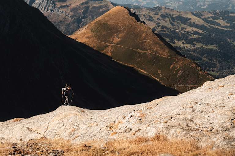 Ein Alpinist steigt einen Berg mit zwei Stöcken und der Haglöfs L.I.M ZT 2.0-Serie hinauf.