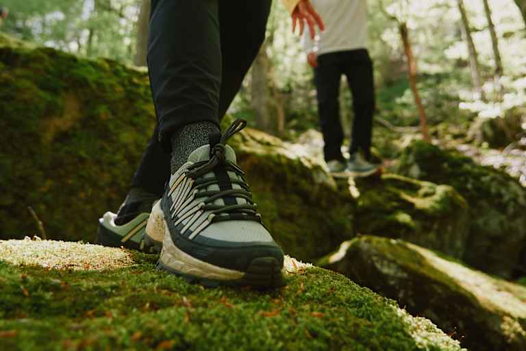 Der Wild Hike Wanderschuh von Jack Wolfskin auf bemoostem Stein in Wald.