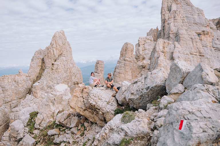 Eine Frau und ein Mann sitzen auf einem Felsen im Eggental.