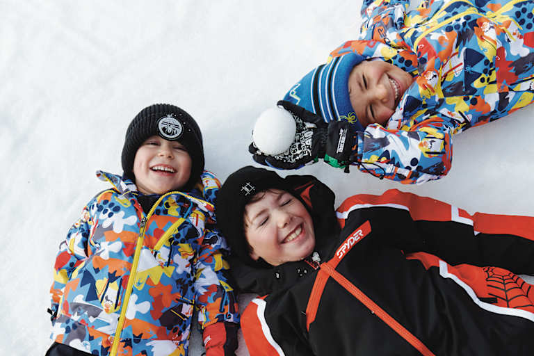 Drei Kinder liegen im Schnee in See.