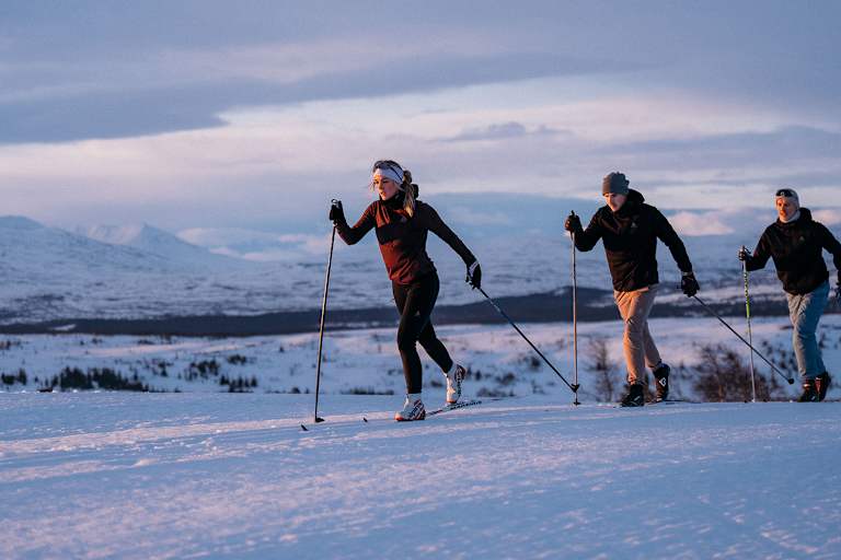 Drei Personen üben die nordische Disziplin Langlaufen aus