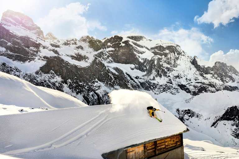 Ein Freerider fährt über das Dach einer Hütte.