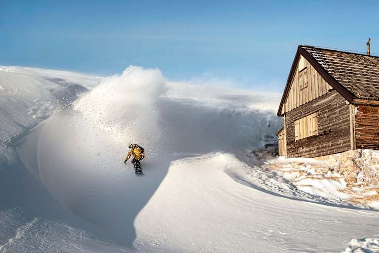 Ein Freerider fährt an einer Hütte vorbei