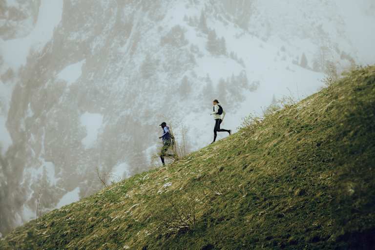 Zwei Trailerunner laufen mit der neuen Salomon Kollektion den Berg hinab.