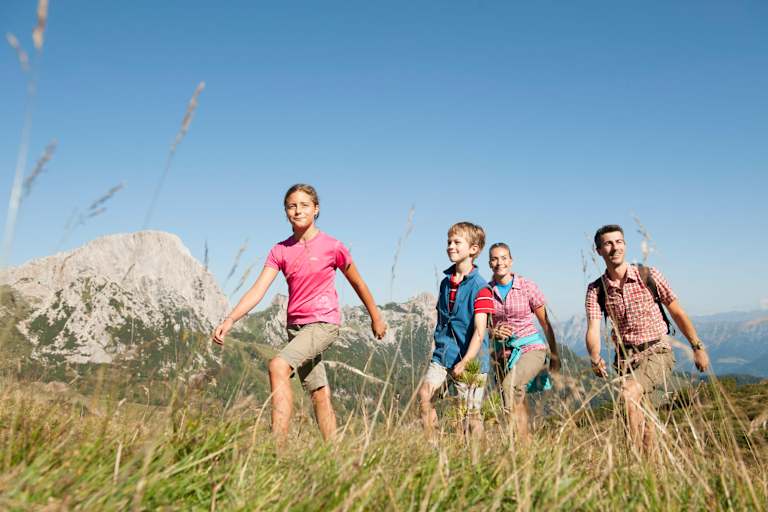 Eine Familie wandert auf einer Alm.