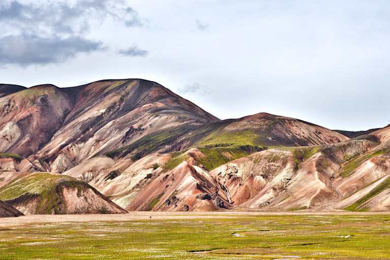 Landmannalaugar: Einsamer Wanderer in der Vulkanlandschaft von Landmannalaugar im Hochland. Buntes Rhyolith-Gestein teils mit Moos überwachsen.