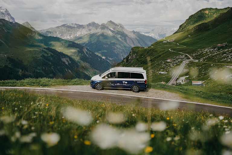 Ein Roadsurfer-Campervan steht am Straßenrand, Blick in die Berge