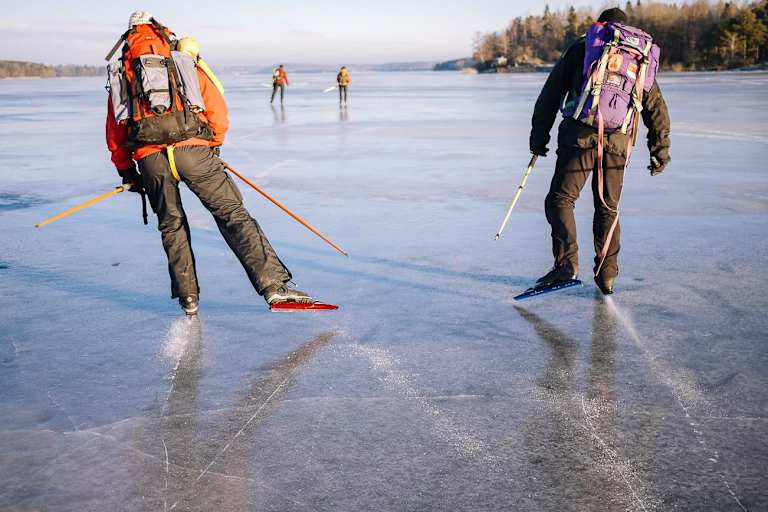 Zwei Nordic Skater mit Rucksäcken auf einem gefrorenen See nahe Uppsala 