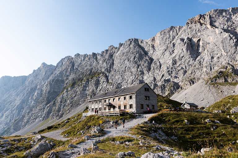 Blick auf die Lamsenjochhütte, die vor gewaltigen Felswänden im Karwendel steht