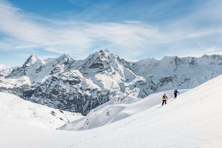 Zwei Schneeschuhwanderer vor atemberaubendem Bergpanorama.