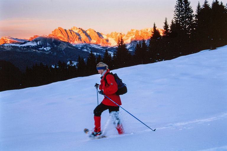 Alpenglühen: Schneeschuhwanderin vor Bergpanorama