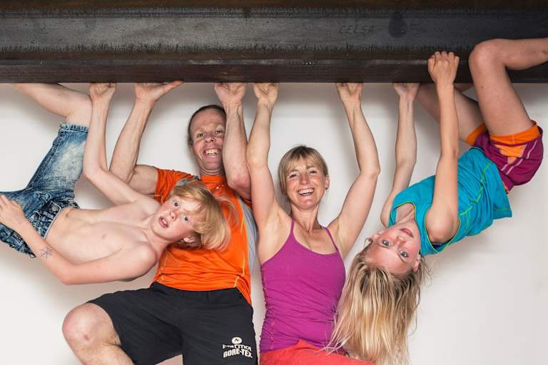 Eine Familie hängt mit den Händen auf einem Eisenträger in der Luft