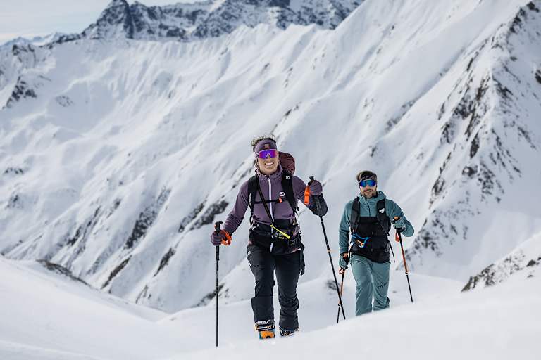 Zwei Skitourengeher auf ihrem Weg durch die verschneite Hochgebirgslandschaft.