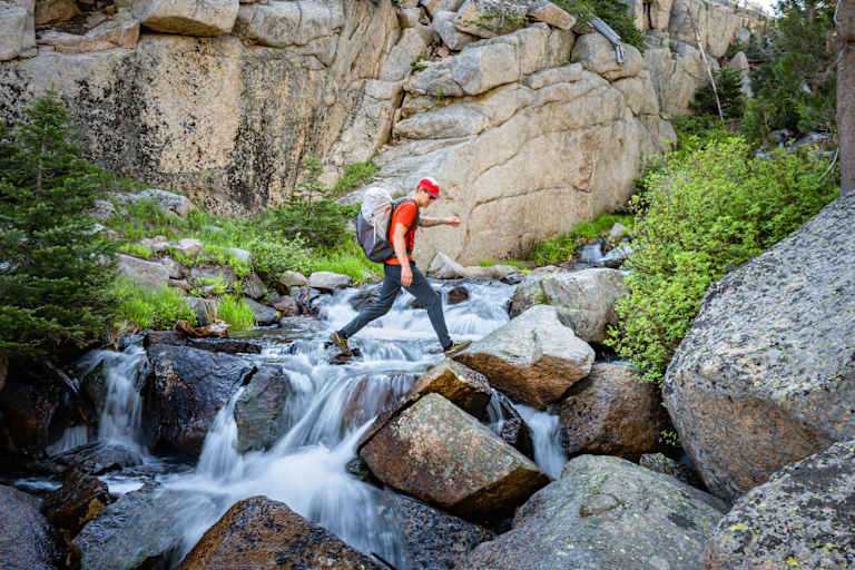 Rab Muon 50L Wanderrucksack mann geht über wasserfall