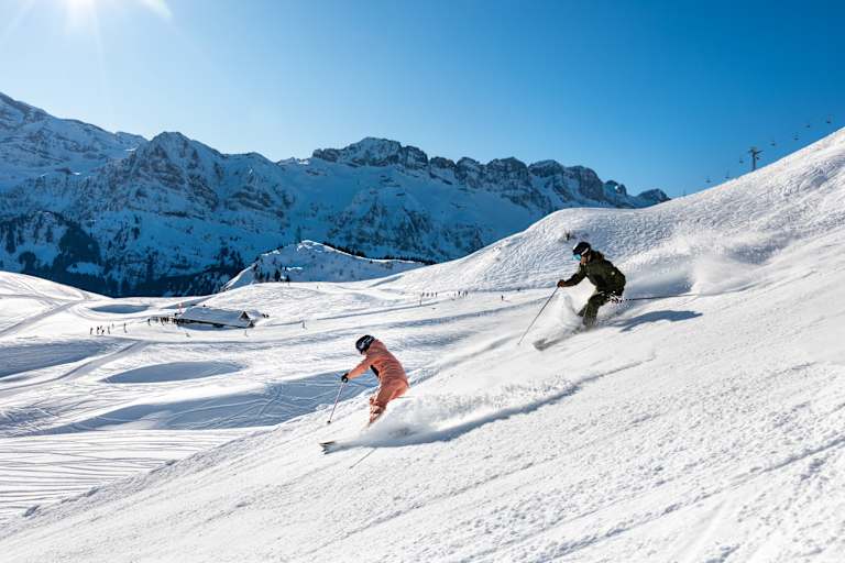 Skifahren in der Schweiz, Berge, zwei Skifahrer, Piste
