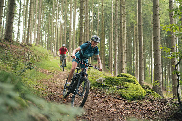 Mountainbiker auf einem naturbelassenen Trail im Wald im Mühlviertel, Oberösterreich – Biken inmitten von Bäumen und grüner Natur.