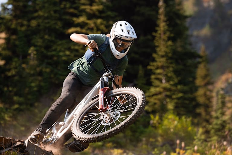 Eine Frau fährt mit dem Mountainbike Waldstrecken ab und trägt dabei einen Helm von ABUS.