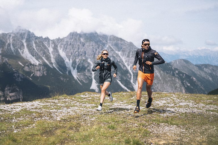 Eine Dame und ein Mann laufen zusammen auf dem Berg.
