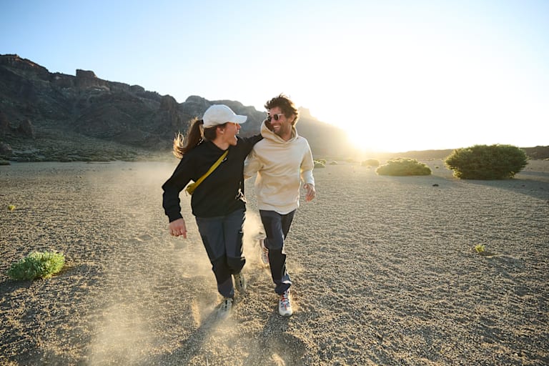 Zwei Personen lachend in der freien Natur mit Kleidung von Maier Sports.