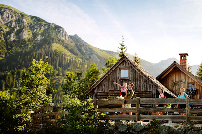 Eine Familie mit 2 Kindern steht auf einer Bergalm in der Steiermark im Sommer und beobachtet die Umgebung.