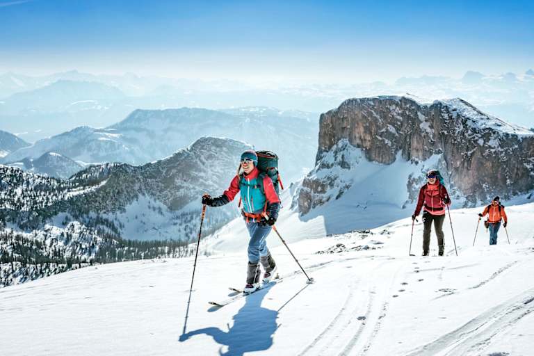 Sportler mit den Skiern am Weg zum Gipfel.