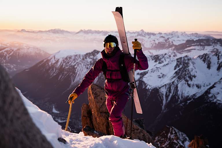 Eine Person steigt mit Tourenski am Rücken auf einen Berg