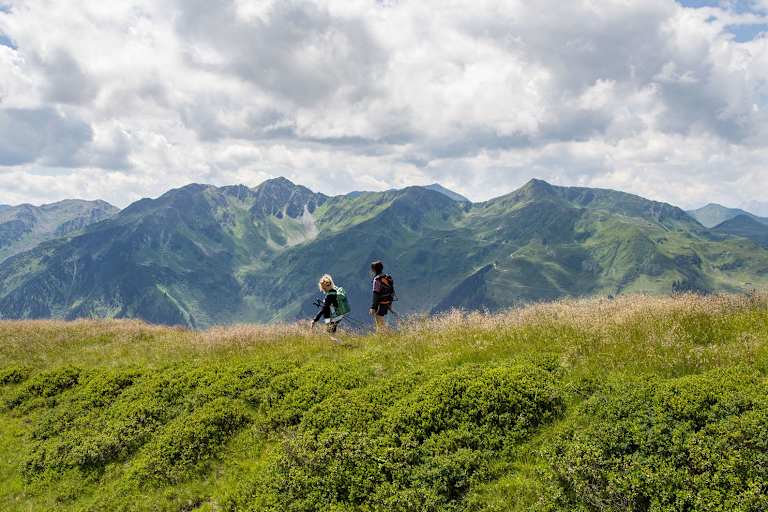 Zwei Frauen spazieren eine begrünte Hügelspitze entlang.