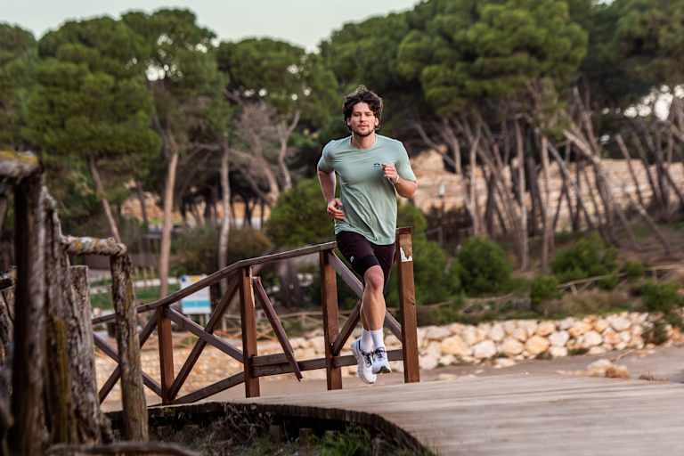 Ein Mann läuft im neuen Trailrunning-Outfit von skinfit über eine Brücke aus Holz.