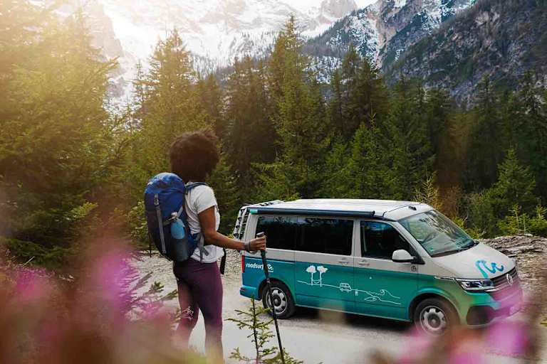 Frau wandert durch die Alpen, unterwegs mit den roadsurfer Camper