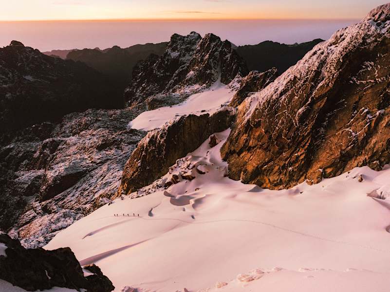 Das Expeditionsteam im sanften Morgenrot auf seinem Weg über den Gletscher. Seit der Erstbesteigung im Jahr 1906 schmilzt das Eis dahin.