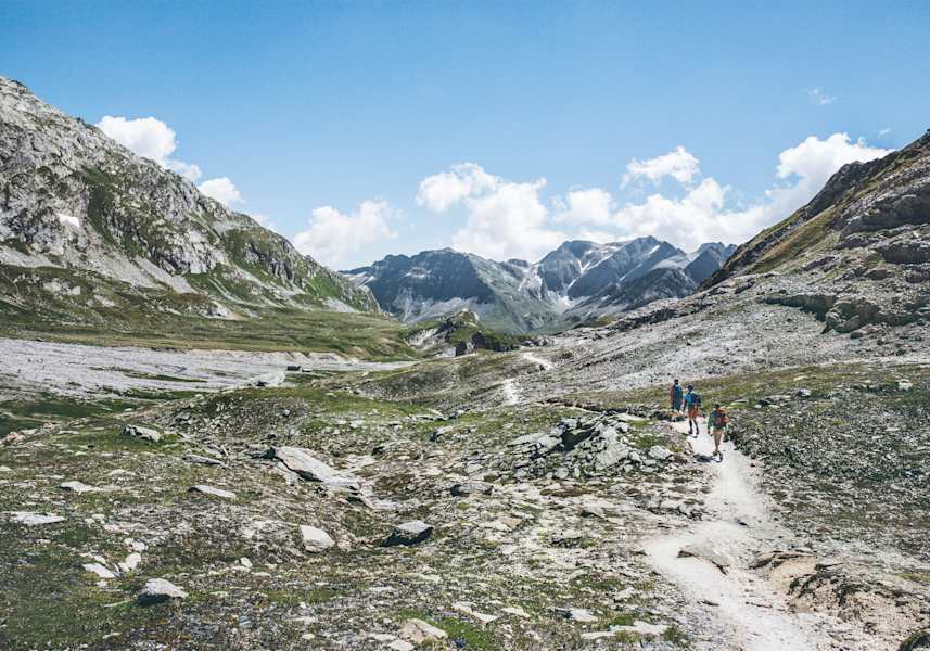 Drei Wanderer auf einem felsigen Weg.