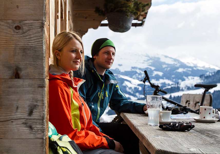 Die beiden FatbikerInnen machen es sich auf der Terrasse der Hütte bequem.