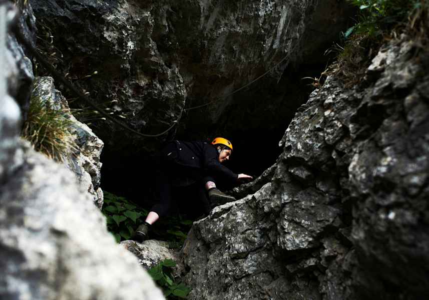 Frau klettert durch eine Felsspalte