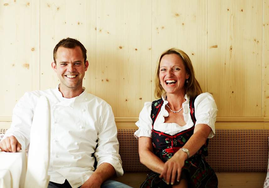 Wirtin und Koch sitzen in der Gaststube auf einer Bank