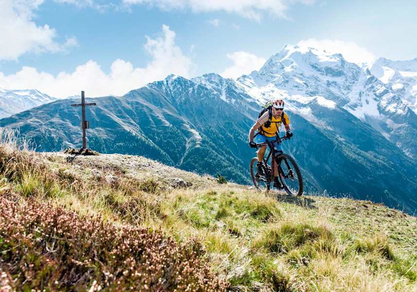 Sigi beim Mountainbiken - mit schneebedeckten Gipfeln im Hintergrund