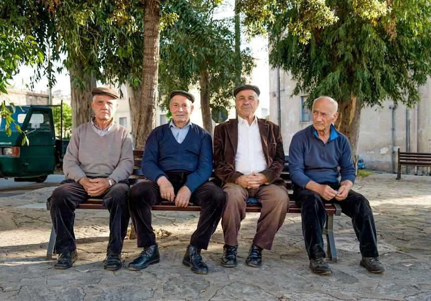 Vier Männern suchen Schatten auf einer Parkbank