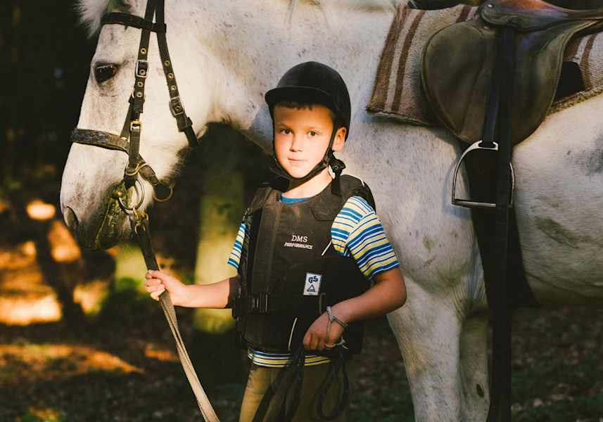 Junge hält sein Pferd am Zaumzeug