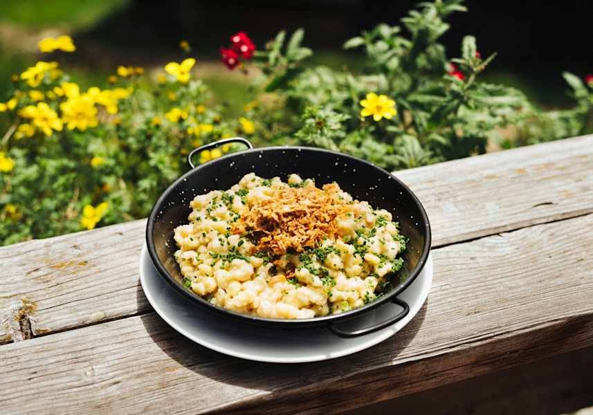 Eine Portion Käsespätzle garniert mit Röstzwiebel und frischen Kräutern