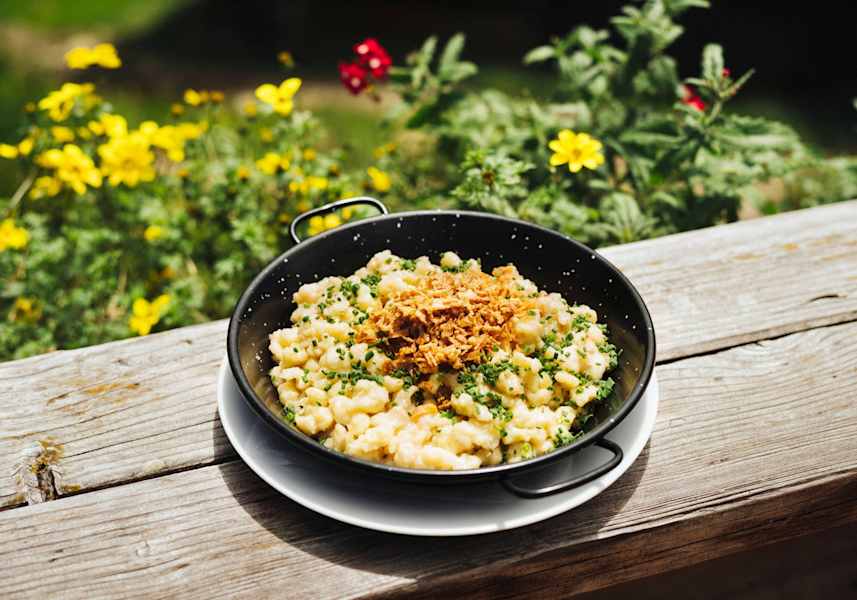 Käsespätzle mit Röstzwiebeln in einer Rein serviert.